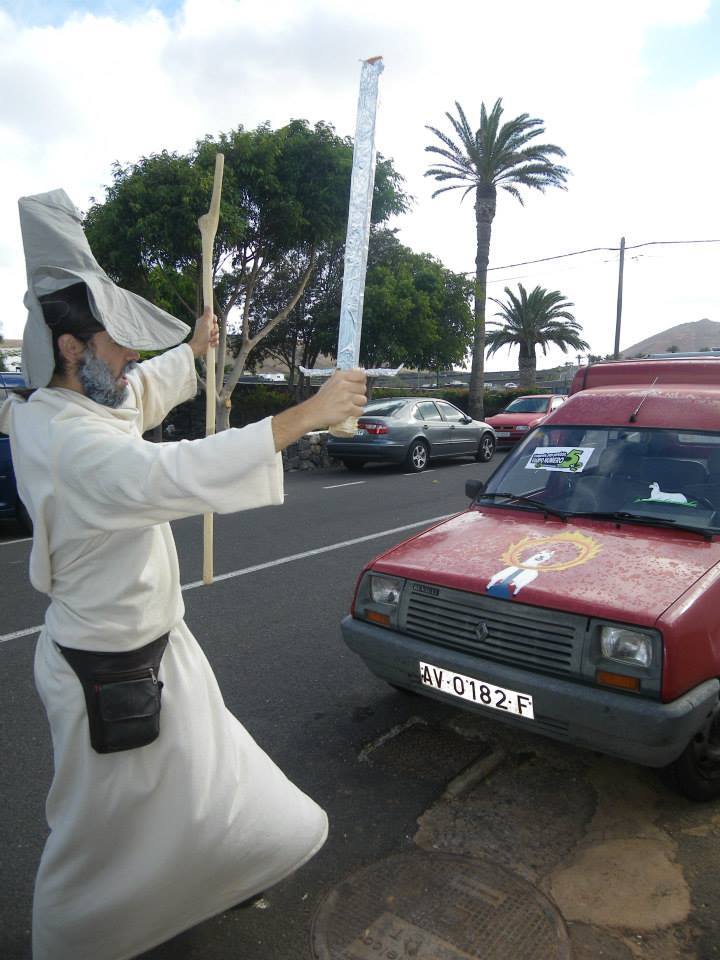 36. Vestido de Gandalf, con barba, túnica, sombrero, báculo y espada; delante de un coche, en la clásica posición de 