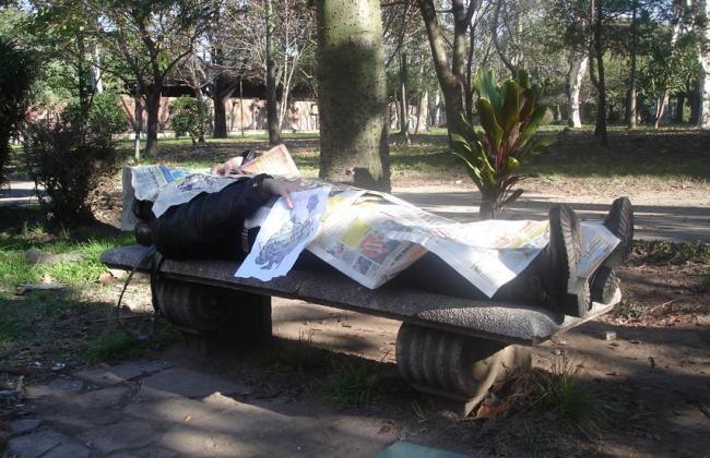 40. Tumbado en el banco de una plaza tapado con periódicos