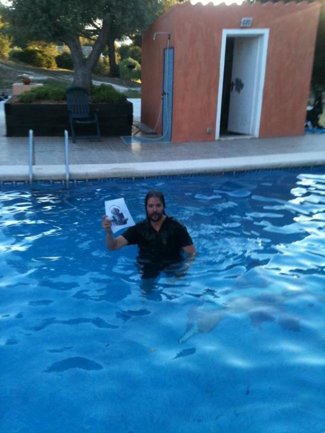 87.-Dentro de una piscina con la ropa puesta y saludando a la cámara.