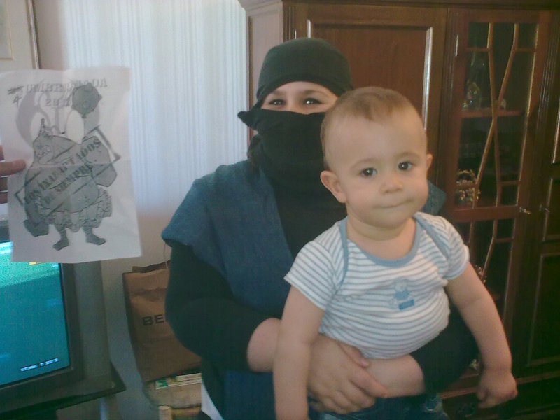 90. Vestido de ninja con un bebe entre los brazos.