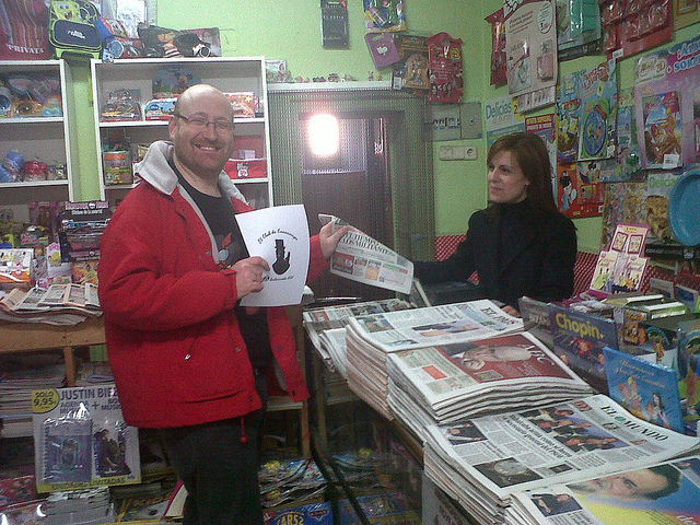 80. En un puesto de diarios y revistas comprando el periodico