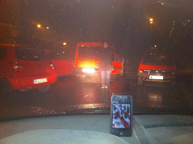 52. Un umbriano/a situado/a entre cuatro coches rojos.