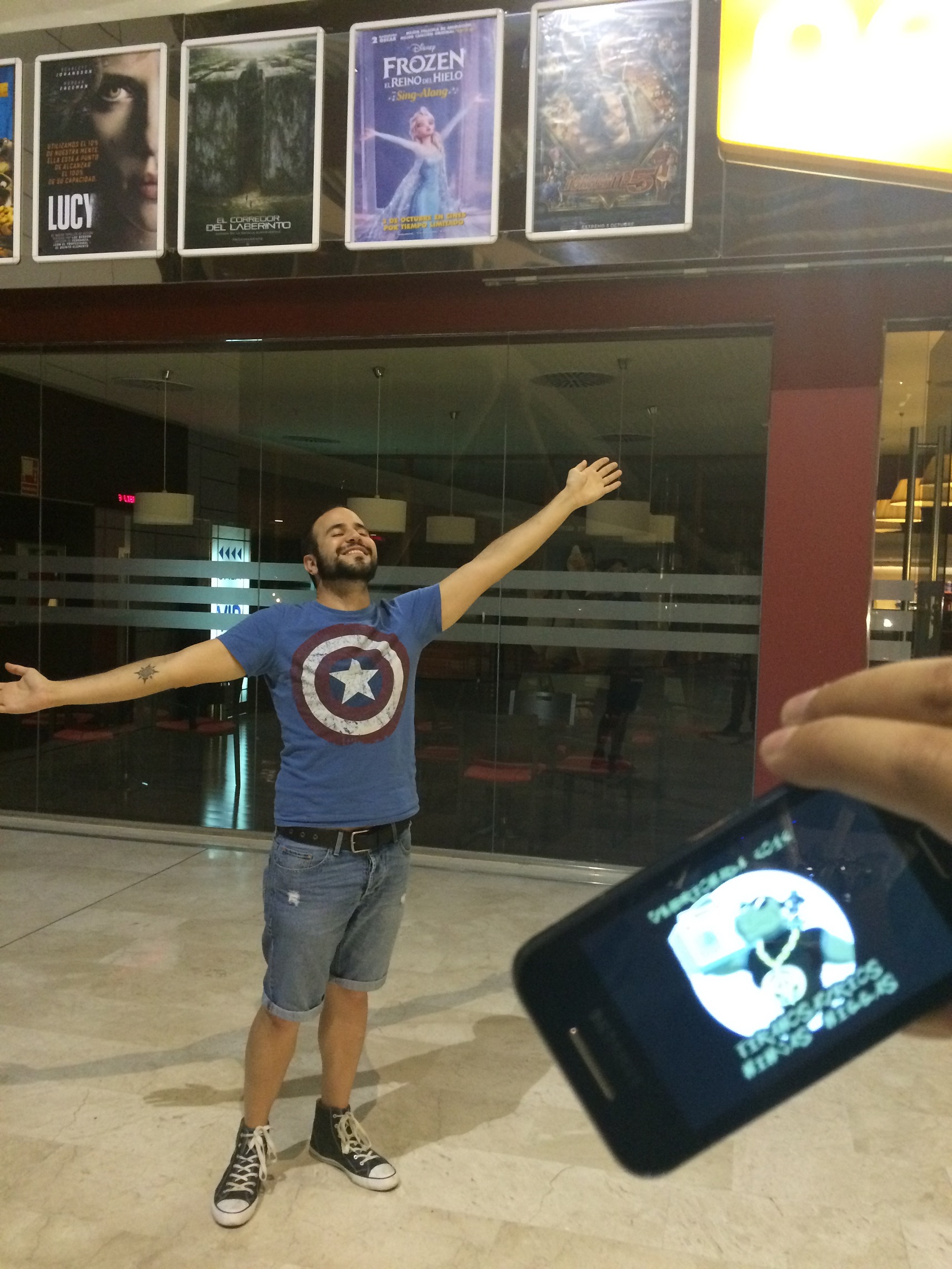 08. En un cine, junto a un póster de una película, imitando las poses de los actores que salen en él.