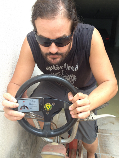 23. Sentado en una motocicleta sosteniendo en las manos un volante de coche.