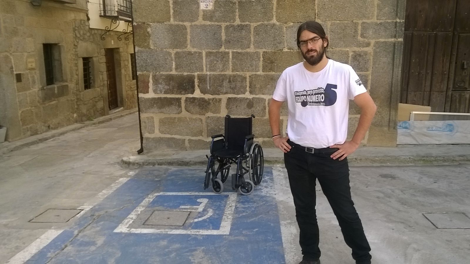 09. Junto a una silla de ruedas vacía que esté en una plaza de parking para minusválidos.