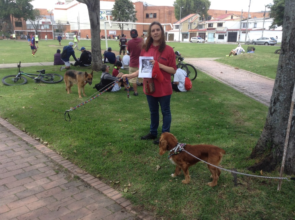 56. Llevando a un perro invisible en un parque al aire libre, en dicho parque deben verse otras personas paseando mascotas de verdad.