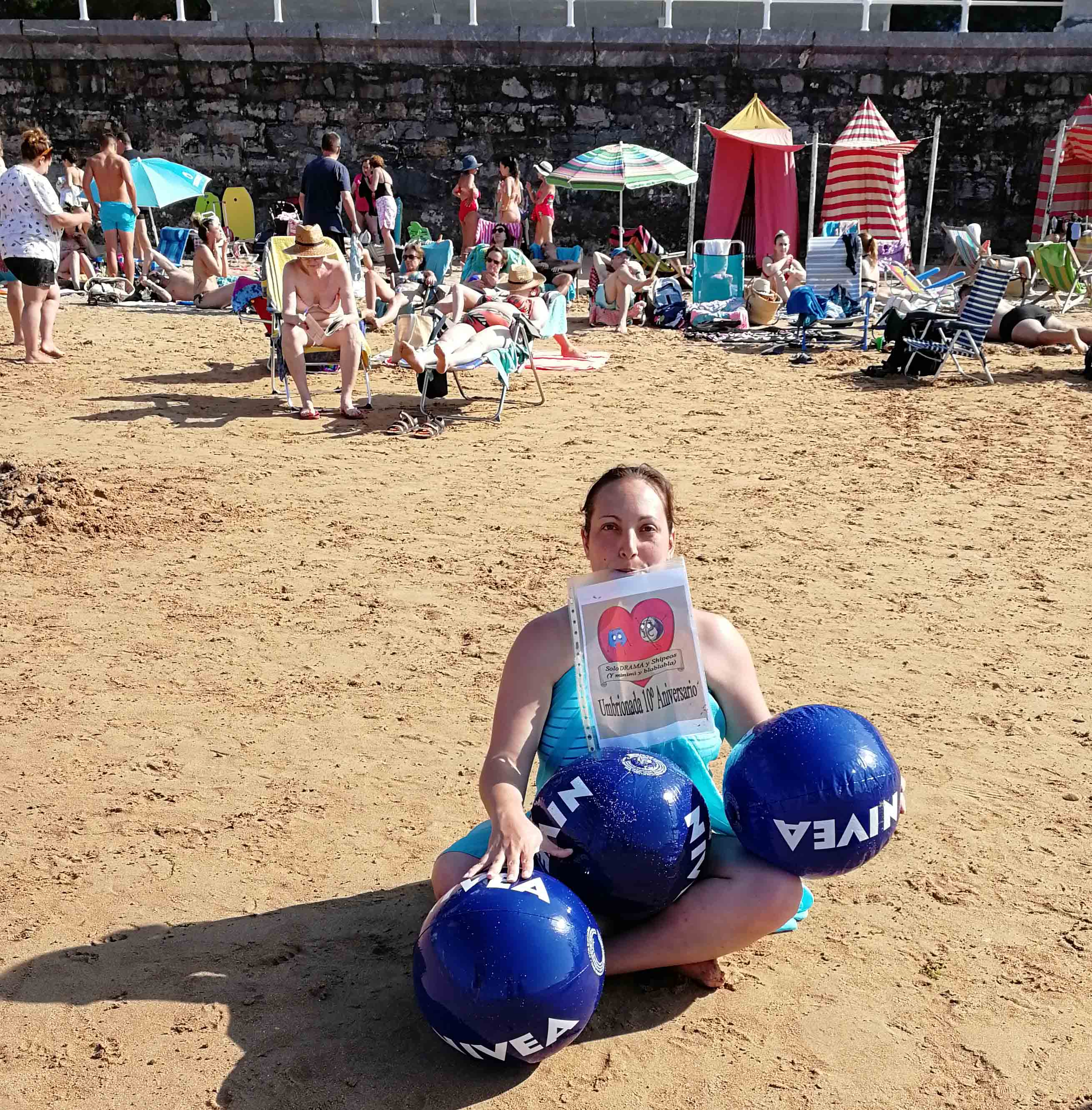 48. Con tres pelotas de playa Nivea infladas, en una playa en donde se vea gente.