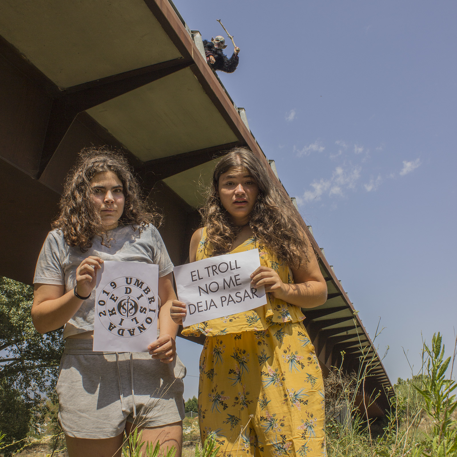 77 Debajo de un puente sosteniendo un cartel en el que se pueda leer: 