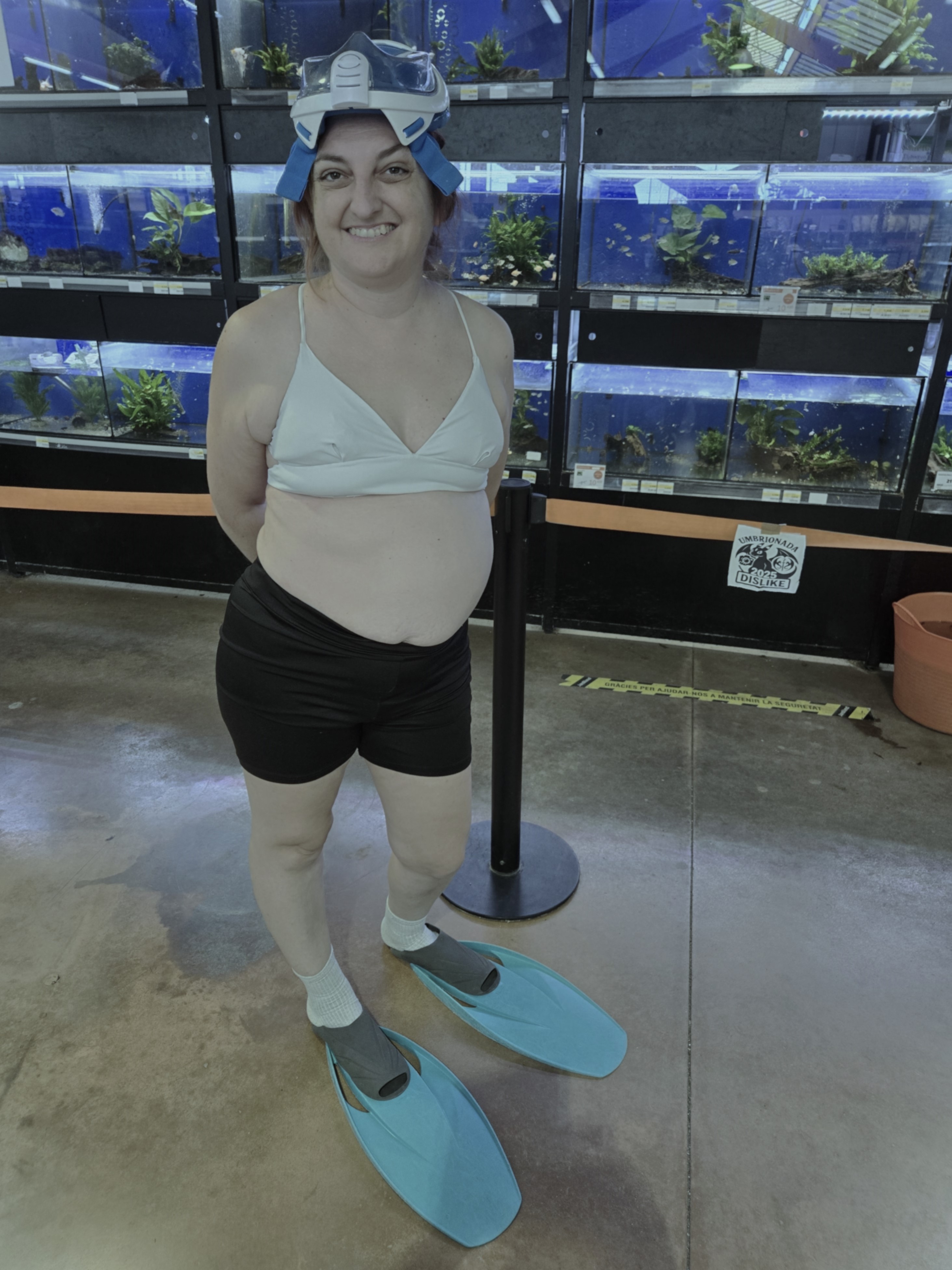 19.	En un acuárium público con snorkel, aletas y bañador puestos junto al cristal donde están los peces