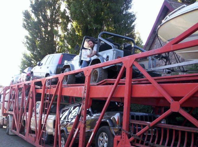 33. Dentro de un coche subido en un camión de transporte de coches.