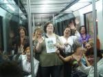 72. En un vagón de metro, tren o tranvía y al menos 10 viajeros saludando a la cámara