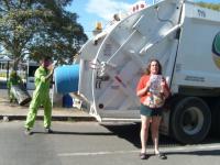 59. Con un basurero de uniforme junto al camión de la basura