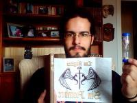 51.Con un ejemplar del libro Momo de Michael Ende, sosteniendo con la otra mano un reloj de arena.