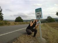 76. Debajo de un cartel de distancia de algún lugar que esté a 42 kilómetros.