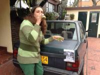 71. Junto a un coche verde, vestido de verde, tomando una bebida verde y mostrando medio kiwi por el lado verde.